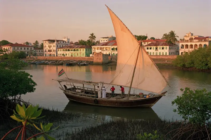 A lateen-sail dhow on the creek beside Mombasa waterfront buildings