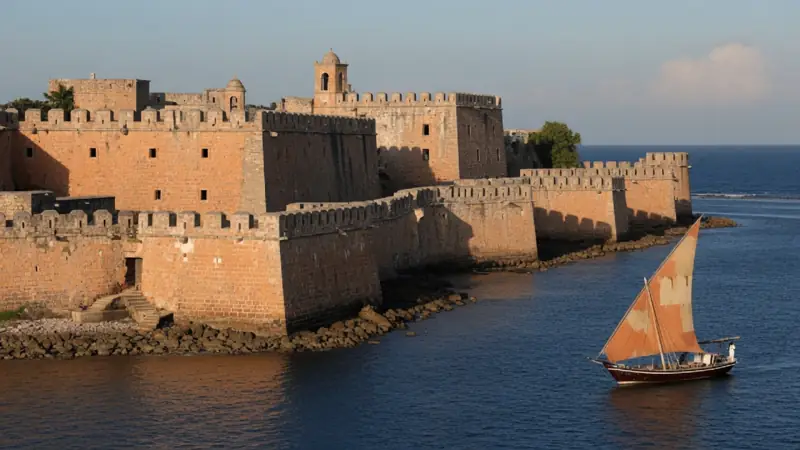 Coral-stone ramparts of Fort Jesus above the Indian Ocean at Mombasa, with a dhow sailing past