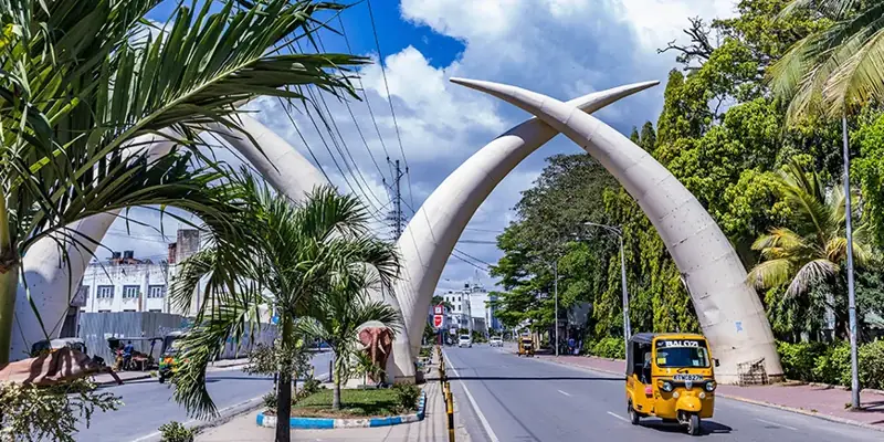The Mombasa Tusks over Moi Avenue, with palms and a yellow tuk-tuk